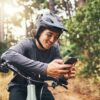 Cycling man in forest, phone gps and map direction with adventure, nature trail and bicycle break i