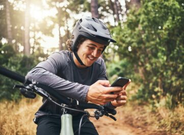 Cycling man in forest, phone gps and map direction with adventure, nature trail and bicycle break i