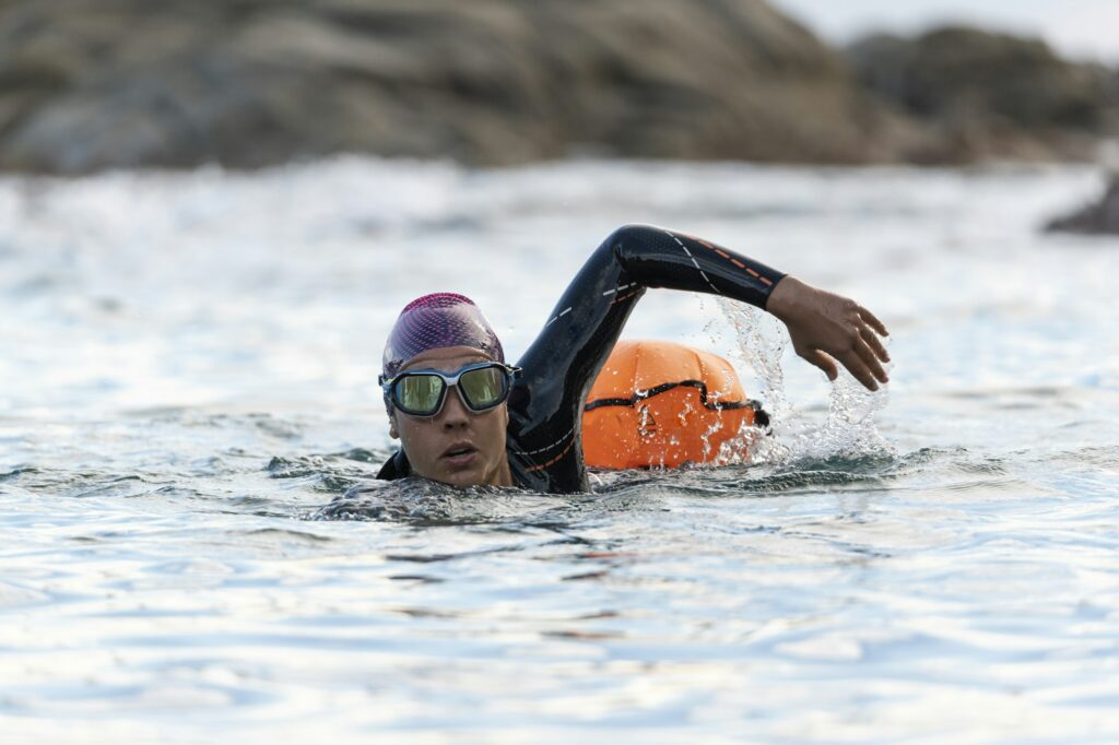 Woman swimming in open water with wetsuit and buoy